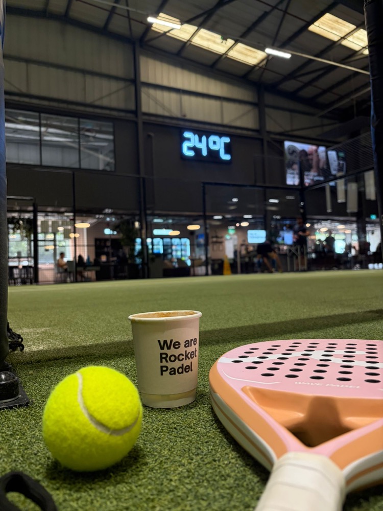 Padel racket, ball and coffee cup courtside at Rocket Padel Bristol